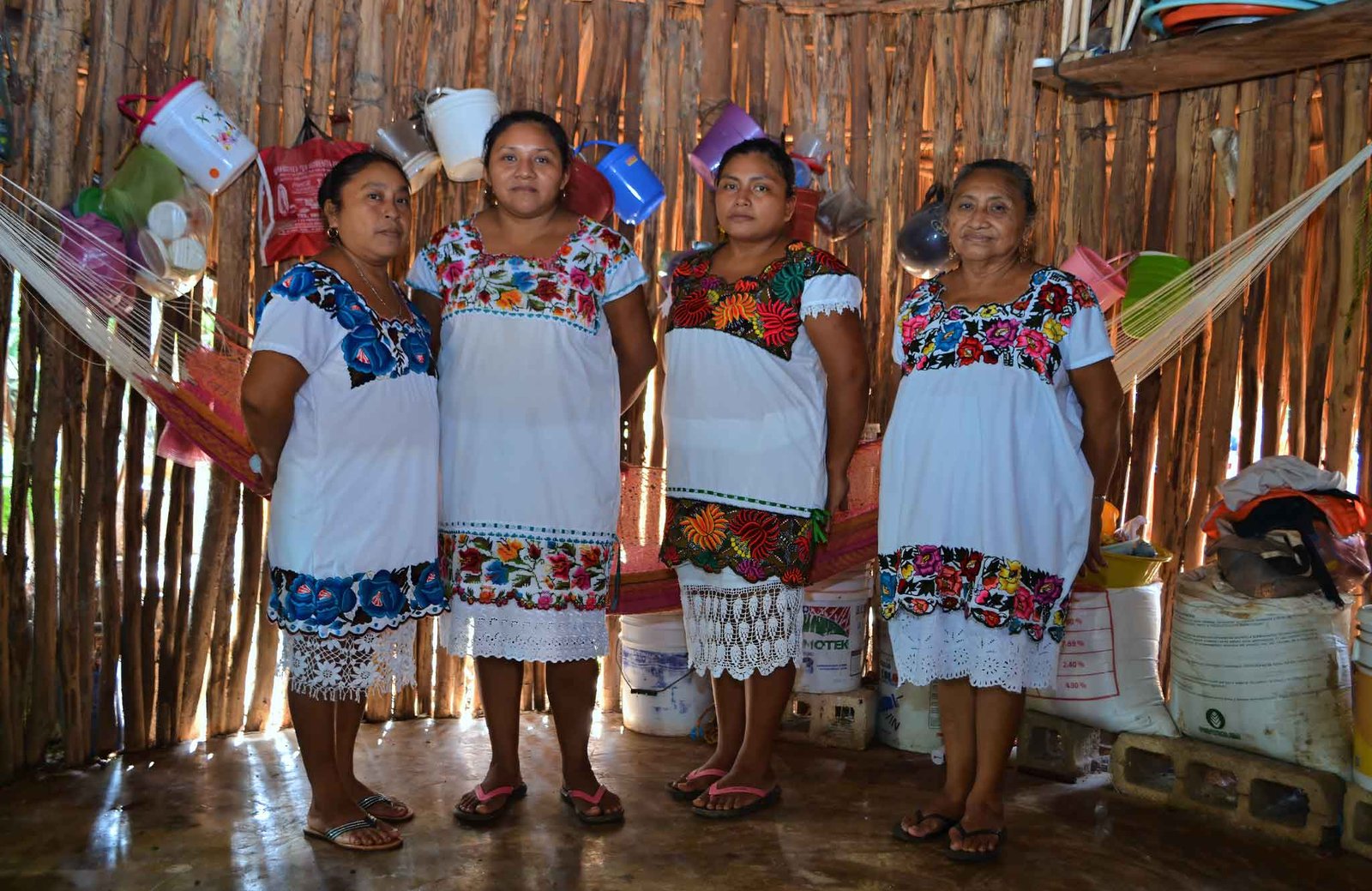 Mayan women from Yucatán dressed in traditional huipils, smiling and standing together as proud hosts of a cultural culinary immersion experience.