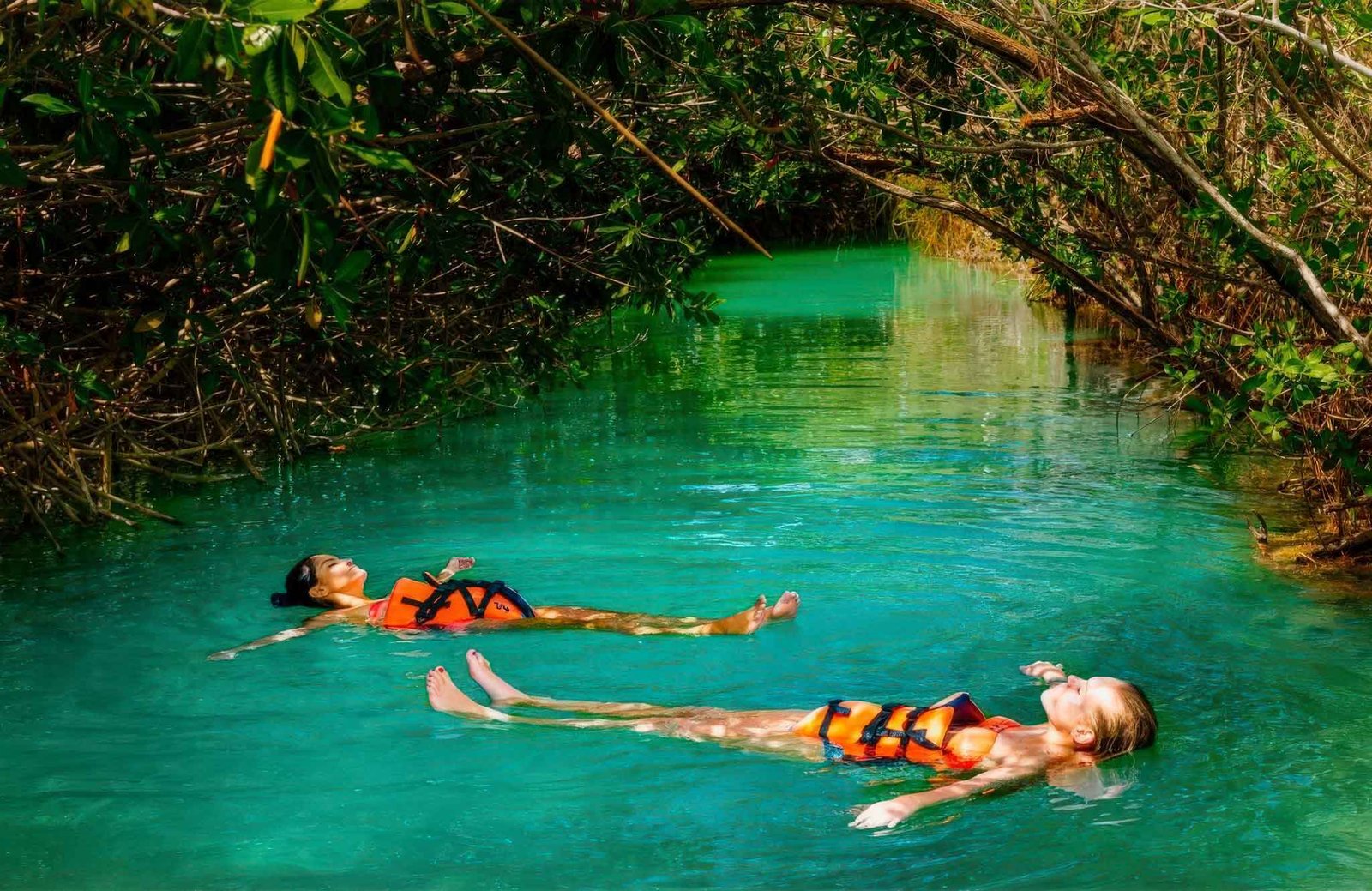 A couple enjoying the serene waters of the Sian Ka'an Biosphere Reserve, surrounded by lush mangroves and peaceful natural beauty.