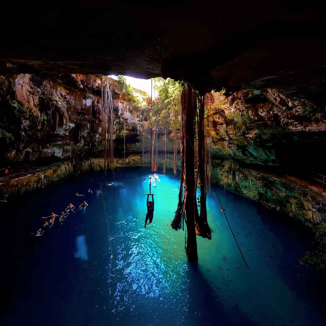 Swimmers in a limestone cenote, part of private Quintana Roo journeys through underground rivers and water systems